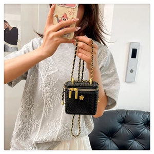 Détail du mini sac boîte noir effet crocodile avec emblème fleur dorée et chaîne