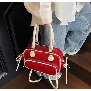 Detail of red and cream contrast leather handbag with white bow accents on the side