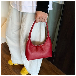 Detail of red dumpling shoulder bag featuring pebbled leather texture and silver zippers