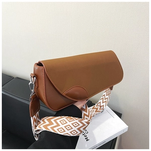 Detail of a brown leather shoulder bag featuring a geometric pattern wide fabric strap
