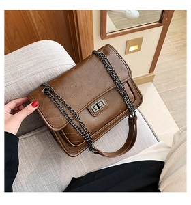 Détail d'un sac bandoulière matelassé marron avec coutures en V et fermoir rotatif