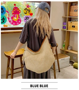 Detail of a large cream woven hobo bag with brown trim and stylish fringe tassels