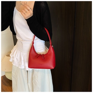 Detail of red pebbled leather hobo bag with dual zippers in a soft indoor setting