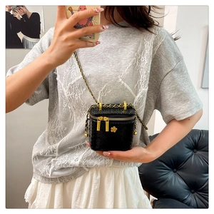 Détail d'un mini sac boîte noir à motif crocodile avec fleur dorée et bandoulière