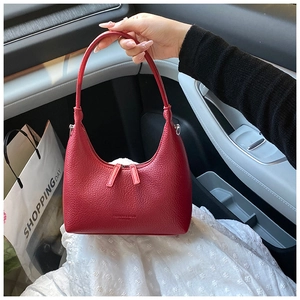 Close-up of red lychee grain leather dumpling bag held inside a car interior