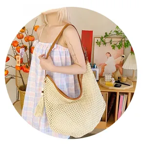 Close-up of woven straw shoulder bag with brown leather trim and white fringe tassel