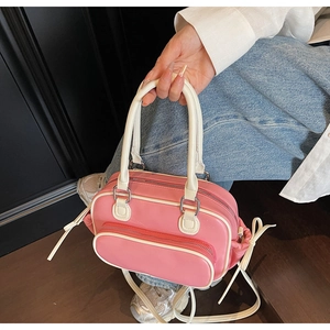 Detailed shot of pink and beige Boston bag with front zipper and bow accent