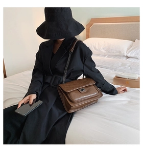 Détail du sac en cuir matelassé marron avec coutures en V et fermoir rotatif en métal