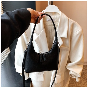 Detail of black pebbled leather half-moon bag with dual silver zippers and handles