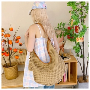 Detail of large woven hobo bag featuring brown leather trim and stylish side tassel
