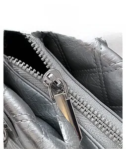 Gros plan sur la fermeture éclair argentée et la texture en cuir matelassé du sac
