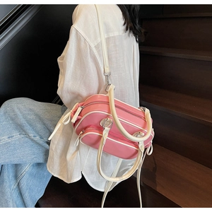 Detail of pink and beige crossbody bag featuring multiple zippers and silver hardware