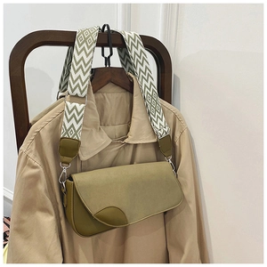 Détail d'un sac besace vert olive avec large bandoulière sur trench-coat kaki