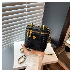 Détail du mini sac boîte noir à motif crocodile avec fermoir fleur de camélia dorée