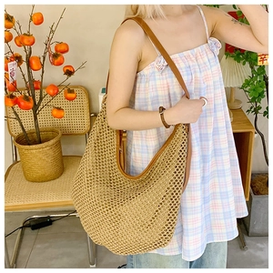 Detail of hand-woven straw shoulder bag with dark brown leather straps and hollow mesh design