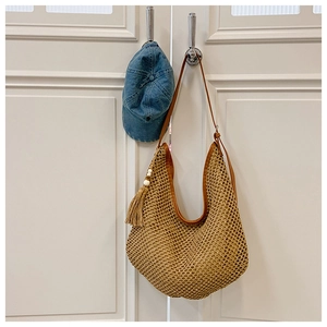 Detailed macro view of bohemian woven bag featuring long tassels and wooden beads