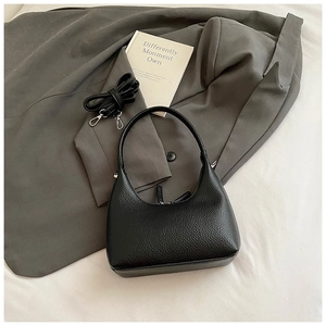 Close-up of black lychee grain leather hobo bag with adjustable strap and suit background