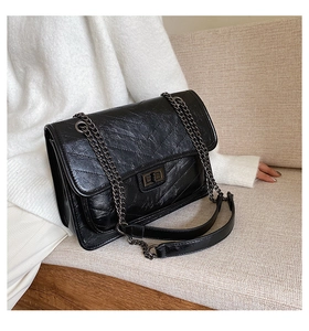 Détail du sac bandoulière matelassé noir avec chaîne métallique et fermoir rotatif