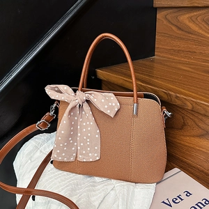 Sac à bandoulière marron tressé avec foulard à pois élégant sur décor en bois