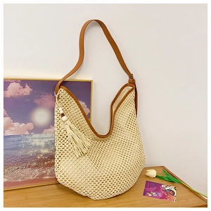 Detail of hollow-out straw bag with brown leather strap and beige tassel for beach vacation