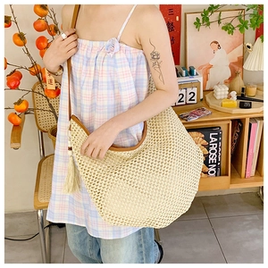 Detail of hollow-out mesh straw hobo bag with brown leather trim and tassel accent