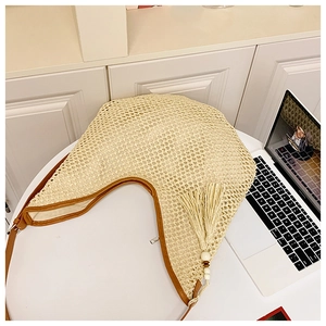 Detailed macro view of beige hollow-out woven texture with brown leather edging and tassel