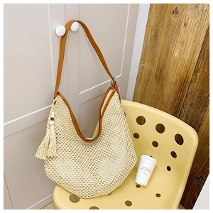 Detail of hand-woven mesh bag with brown leather strap and decorative wood bead tassel