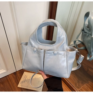 Detail view of light blue glossy PU tote bag with twin buckle pockets and detachable strap