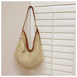 Detail of bohemian straw shoulder bag with crochet texture and brown faux leather strap