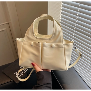 Detail of the cream white PU leather handbag featuring decorative pockets and slim strap