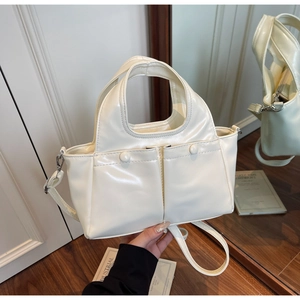 Detail of cream white leather handbag featuring dual front flap pockets and a fixed handle