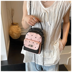 Detail of mini contrast color backpack with pink bow pattern and metal chain strap