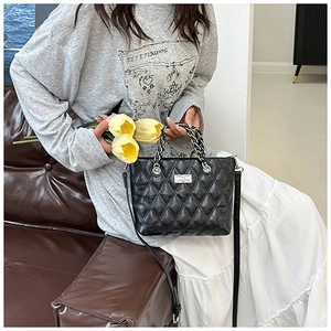 Détail du sac cabas matelassé noir avec poignée en chaîne argentée et fermoir métal