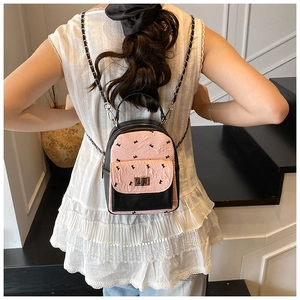 Detail of pink quilted mini backpack with black bow pattern and chain straps on model
