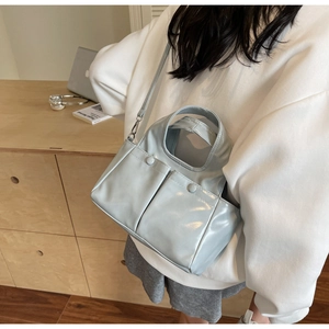 Detail of light blue crossbody bag with double front flap pockets and glossy finish