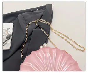 Vue détaillée du sac de soirée rose en forme de coquille avec perles et chaîne dorée