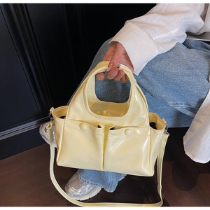 Detail of pale yellow patent leather handbag with dual pockets and high-gloss finish