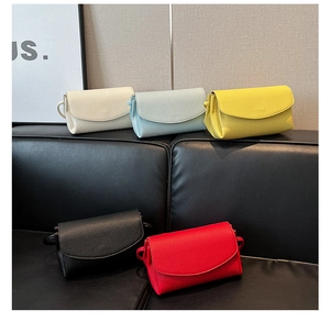Detail of five soft leather crossbody bags in various colors on a black leather bench