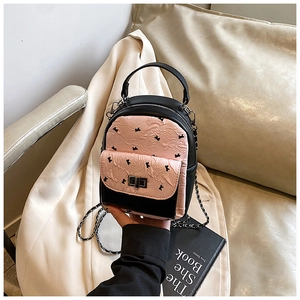 Detail of pink quilted handbag with black bow prints and elegant silver chain strap