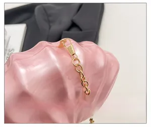 Détail de la pochette de soirée rose en forme de coquillage avec lustre nacré et chaîne dorée
