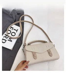 Detail of cream fabric handbag with leather strap and metal button on white background