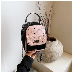 Detail of pink quilted flap on black mini backpack with silver metal twist lock and chain