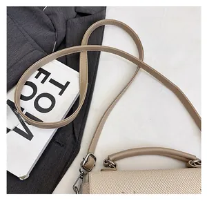 Detail of adjustable leather strap and silver buckle on apricot woven handbag