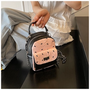 Close-up of mini quilted backpack featuring pink bow patterns and a metal clasp lock
