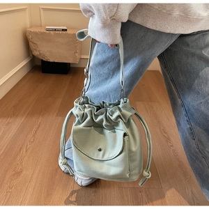Detail of mint green canvas bucket bag with drawstring closure and metal snap pocket