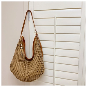 Close-up of woven hollow mesh texture and brown leather strap on a large beach tote
