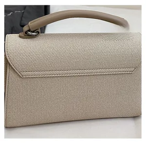 Close-up of textured beige woven handbag with smooth leather handle and silver hardware