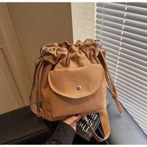 Detail of khaki canvas bucket bag with drawstring closure and silver snap button front pocket