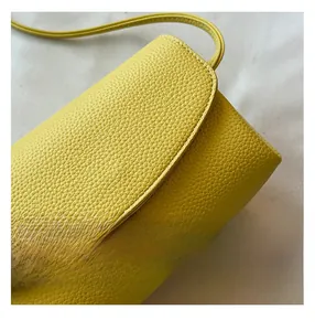 Detailed macro view of yellow lychee grain leather crossbody bag with neat stitching