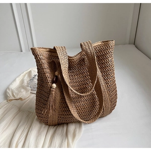 Detail of hand-woven straw tote with hollow mesh pattern and boho tassel wood beads
